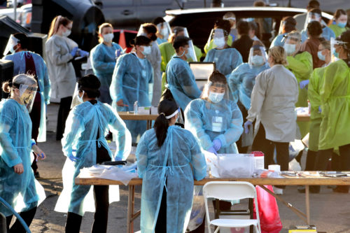 Medical personnel prepare to test hundreds of people lined up in vehicles in Phoenix, Arizona. The state has issued a new shutdown order after a sharp increase in coronavirus infections. AP Photo/Matt York