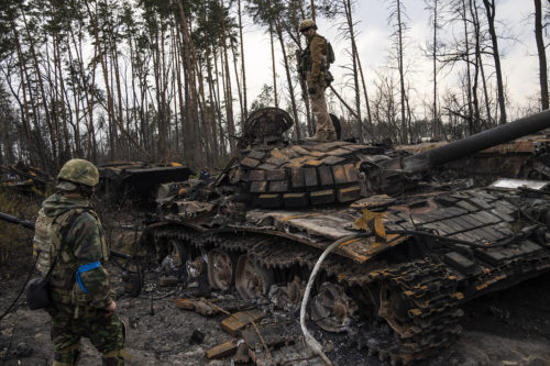 A Ukrainian soldier stands one top of a destroyed Russian tank on the outskirts of Kyiv, Ukrain. AP Photo/Rodrigo Abd