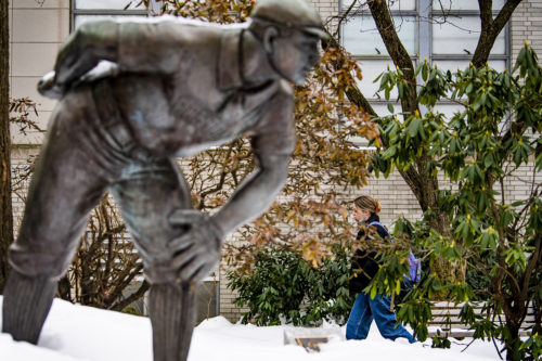 A member of the Northeastern community walks by the Cy Young statue surrounded by snow on the Boston campus. Photo by Alyssa Stone/Northeastern University