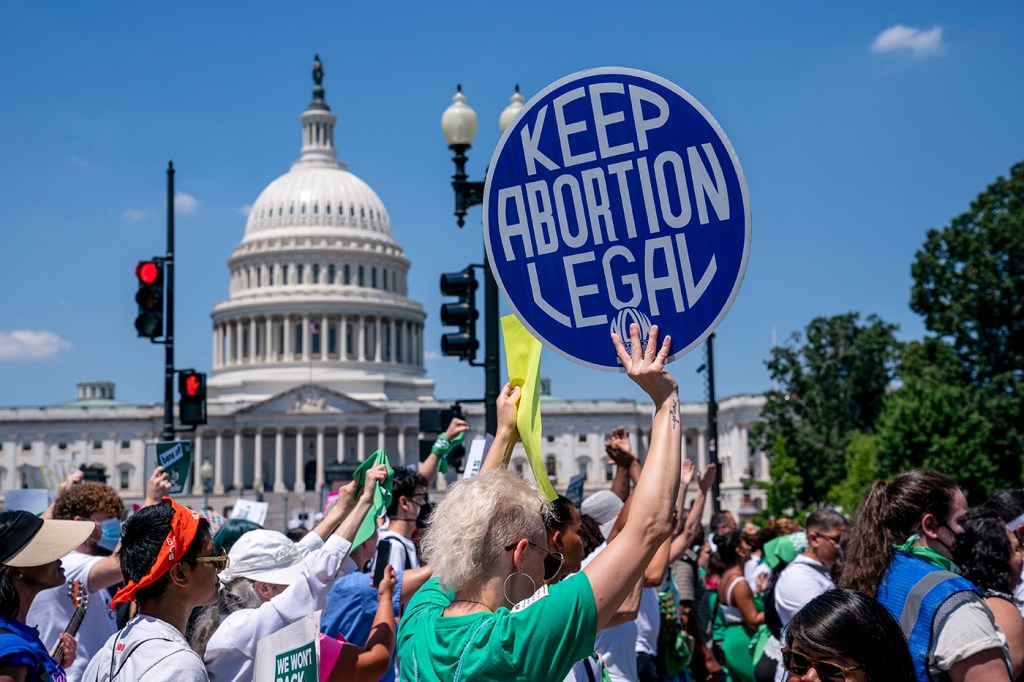 person holding 'keep abortion legal' protest sign on capitol hill
