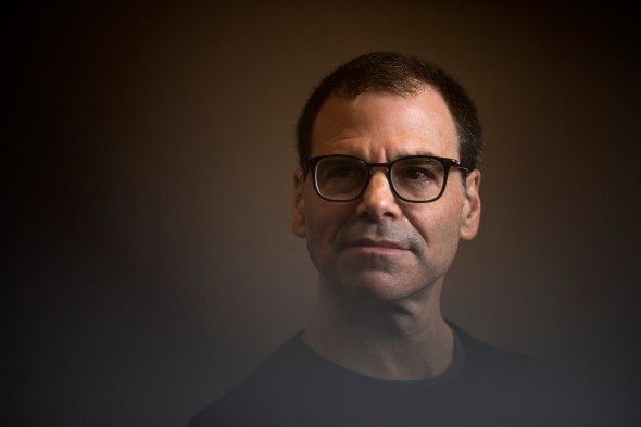 man wearing glasses in front of a brown background