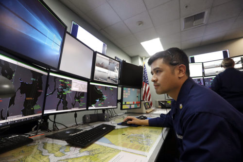 In this Wednesday, Jan. 16, 2019 file photo, U.S. Coast Guardsmen Gustavo Rosas, who missed his first paycheck a day earlier during the partial government shutdown, monitors marine vessel traffic at Sector Puget Sound base in Seattle. (AP Photo/Elaine Thompson, File)