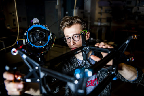 Northeastern computer engineering student Philip Andress makes adjustments to the cable driven robot in the Richards Hall lab where NURobotics meets and works.