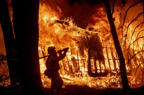 Firefighter Jose Corona sprays water as flames  consume a home in Magalia, California, on Friday, Nov. 9, 2018. (AP Photo/Noah Berger)