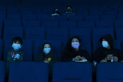 Visitors wear face masks while watching a presentation in a theater at the Aquarium of the Pacific on its first day of reopening to public in Long Beach, Calif. on March 16, 2021.