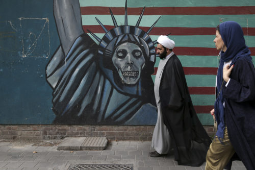 A cleric and a woman walk past an anti-U.S. mural painted on the wall of the former U.S. Embassy in Tehran, Iran, Tuesday, May. 8, 2018. (AP Photo/Vahid Salemi)