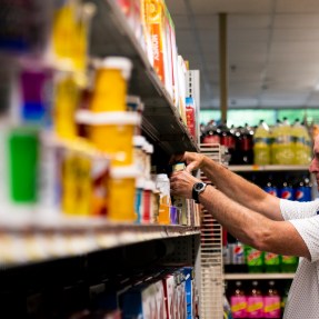 man organizing cans on a grocery shelf