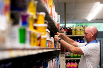 man organizing cans on a grocery shelf