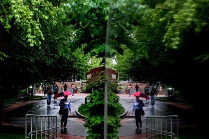 Northeastern students are seen reflected in the Veterans Memorial while walking through campus on a rainy Monday. Photo by Matthew Modoono/Northeastern University