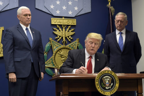President Donald Trump, center, with Vice President Mike Pence, left, and Defense Secretary James Mattis, right, watching, signs an executive action on extreme vetting at the Pentagon on Friday. (AP Photo/Susan Walsh)