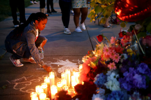 A woman chalks a message at a makeshift memorial outside of Tops market on May 15, 2022 in Buffalo, New York. A gunman opened fire at the store killing ten people and wounding another three. The attack was believed to be motivated by racial hatred. Photo by Scott Olson/Getty Images
