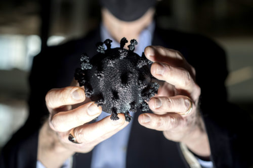 Lee Makowski, chair of the bioengineering department, holds a 3D printed model of COVID-19 showing spike proteins on the surface. Photo by Matthew Modoono/Northeastern University