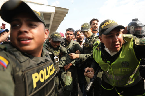 Colombian police escort a Venezuelan soldier who defected at the Simon Bolivar international bridge, where Venezuelans tried to deliver humanitarian aid despite objections from President Nicolas Maduro, in Cucuta, Colombia, Saturday, Feb. 23, 2019. (AP Photo/Fernando Vergara)