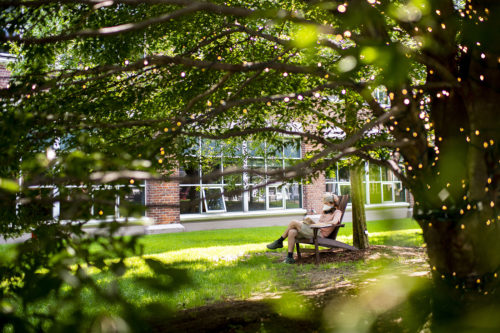B Parazin, who studies physics, finds a cool spot on Centennial Common to enjoy a book during a heatwave. Photo by Ruby Wallau/Northeastern University