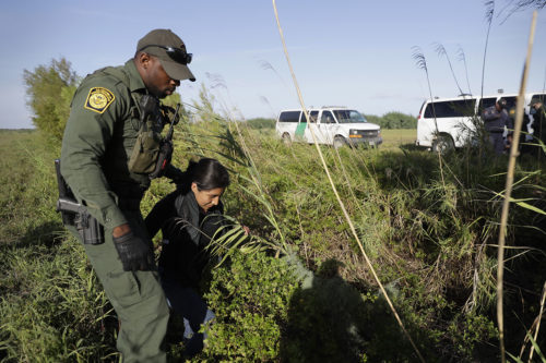 In this Aug. 11, 2017, photo a U.S. Customs and Border Patrol agent escorts an immigrant suspected of crossing into the United States illegally along the Rio Grande near Granjeno, Texas. The election of President Donald Trump contributed to a dramatic downturn in migration, causing the number of arrests at the border to hit an all-time low in April. But since then, the number of immigrants caught at the southern border has been increasing monthly. (AP Photo/Eric Gay)