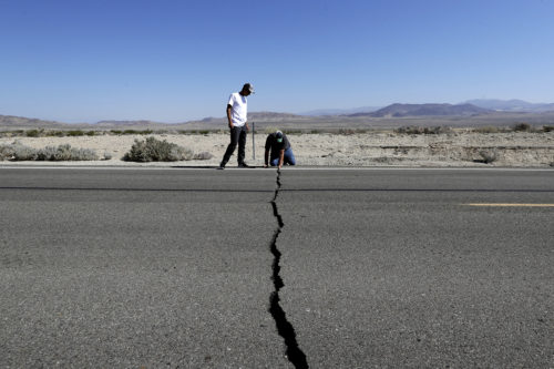 Ron Mikulaco, right, and his nephew, Brad Fernandez, examine a crack caused by an earthquake on Highway 178, Saturday, July 6, 2019, outside of Ridgecrest, Calif. Crews in Southern California assessed damage to cracked and burned buildings, broken roads, leaking water and gas lines and other infrastructure Saturday after the largest earthquake the region has seen in nearly 20 years jolted an area from Sacramento to Las Vegas to Mexico. (AP Photo/Marcio Jose Sanchez)