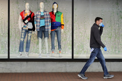 A man walks past mannequins in the windows of the Macy's store in the Downtown Crossing area of Boston, on April 15, 2020. U.S. retail sales plummeted in March, an unprecedented decline, as the viral outbreak forced an almost complete lockdown of commerce nationwide.  AP Photo/Charles Krupa