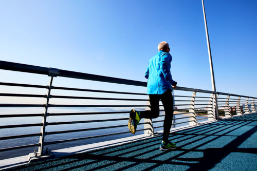 man in a blue jacket running on a bridge