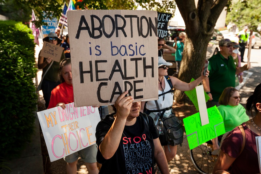 protestors holding a sign that says 'abortion is basic health care'