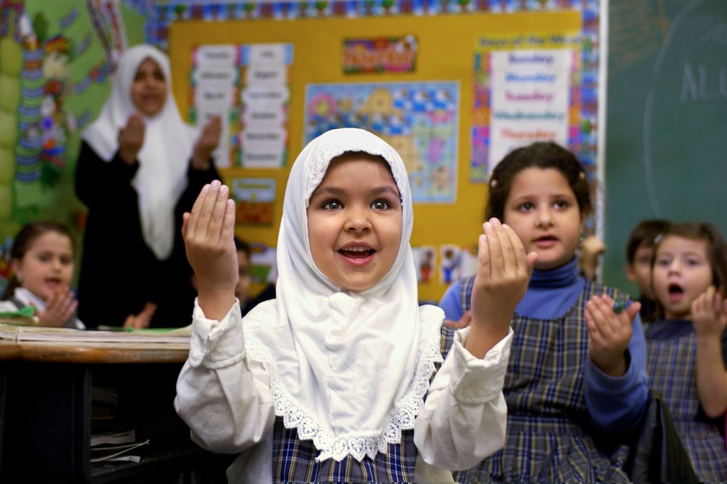 muslim child wearing hijab with her hands in the air