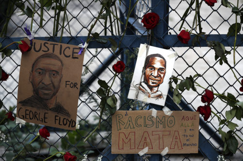 Images of George Floyd, a handcuffed black man who died after being taken into police custody in Minneapolis, hang surrounded by roses on a security barrier outside the U.S. embassy in Mexico City on May 30, 2020. AP Photo by Rebecca Blackwell