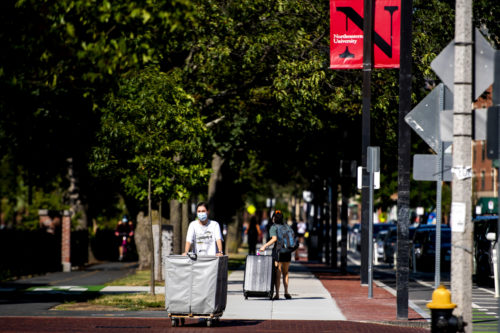 A student wearing a face mark walks pushes a moving bin down Columbus Ave on August 18, 2020. Photo by Ruby Wallau/Northeastern University