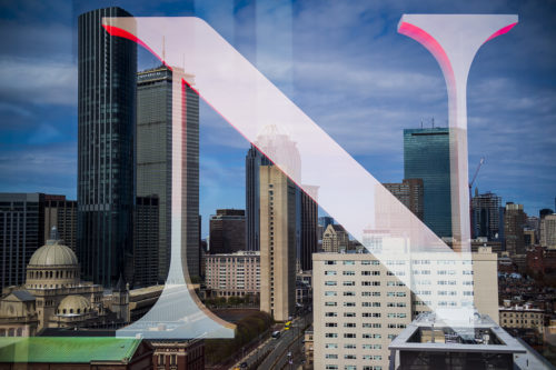 The Boston skyline is seen in a double exposure of the Northeastern “N” from the East Village. Photo by Alyssa Stone/Northeastern University