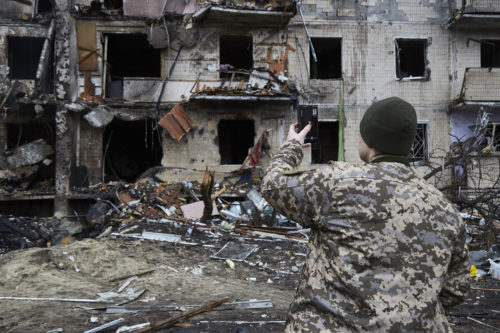 A Ukrainian soldier speaks on his smartphone outside a residential building damaged by a missile on February 25, 2022 in Kyiv, Ukraine. Yesterday, Russia began a large-scale attack on Ukraine, with Russian troops invading the country from the north, east and south, accompanied by air strikes and shelling. The Ukrainian president said that at least 137 Ukrainian soldiers were killed by the end of the first day.  Photo by Pierre Crom/Getty Images