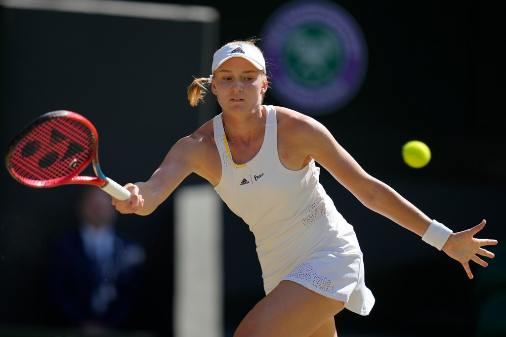 woman wearing all white tennis outfit swinging for a tennis ball