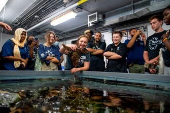 students gather around lobster touch tank