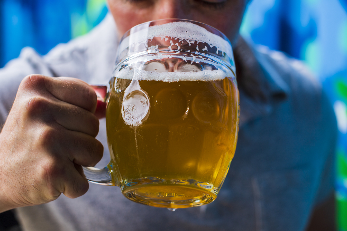 A person is holding a glass of beer, sipping the drink. 
