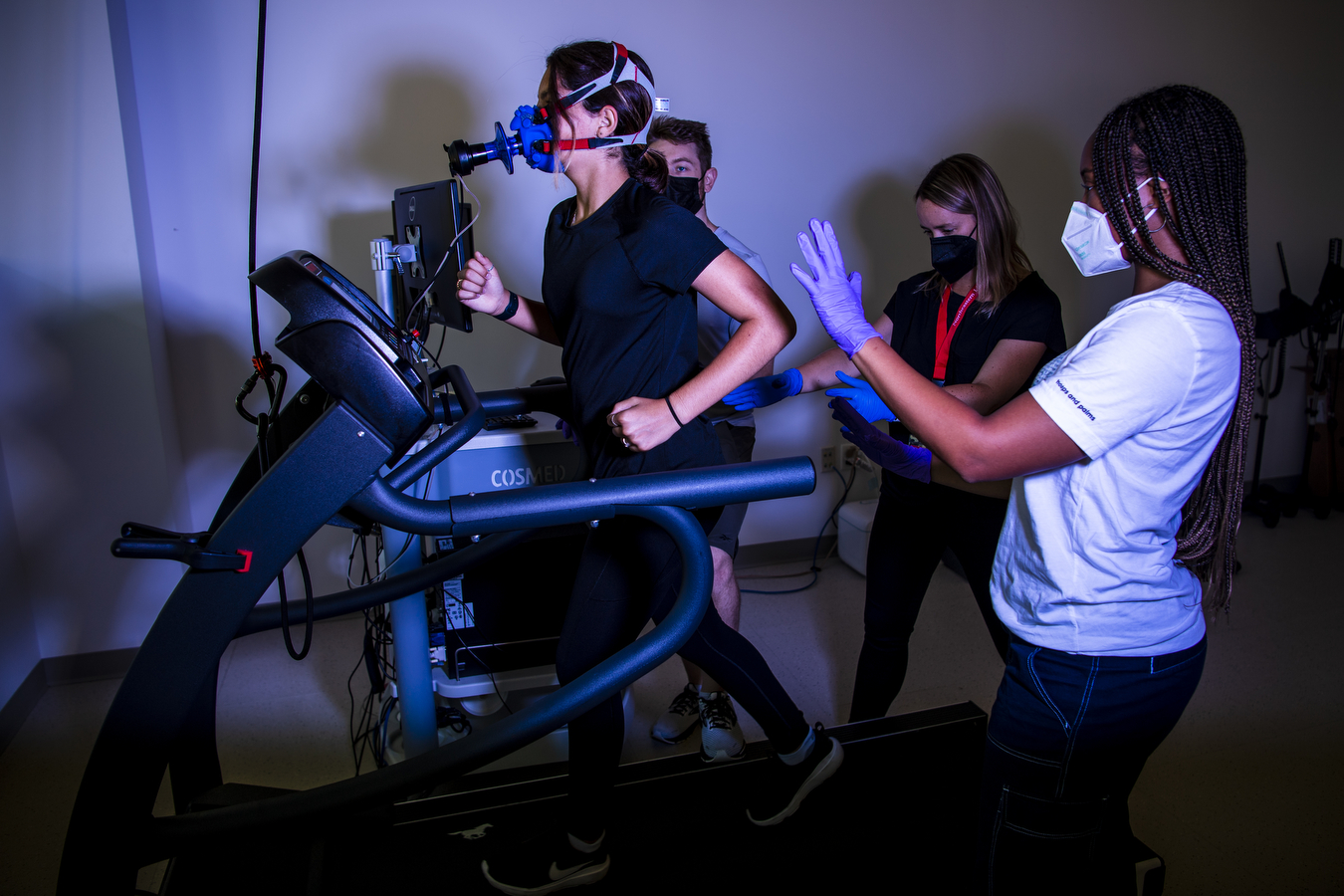 a study participant runs on a treadmill while three researchers look on