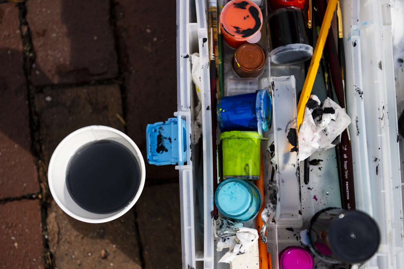 A colorful messy array of paints on the brick sidewalk