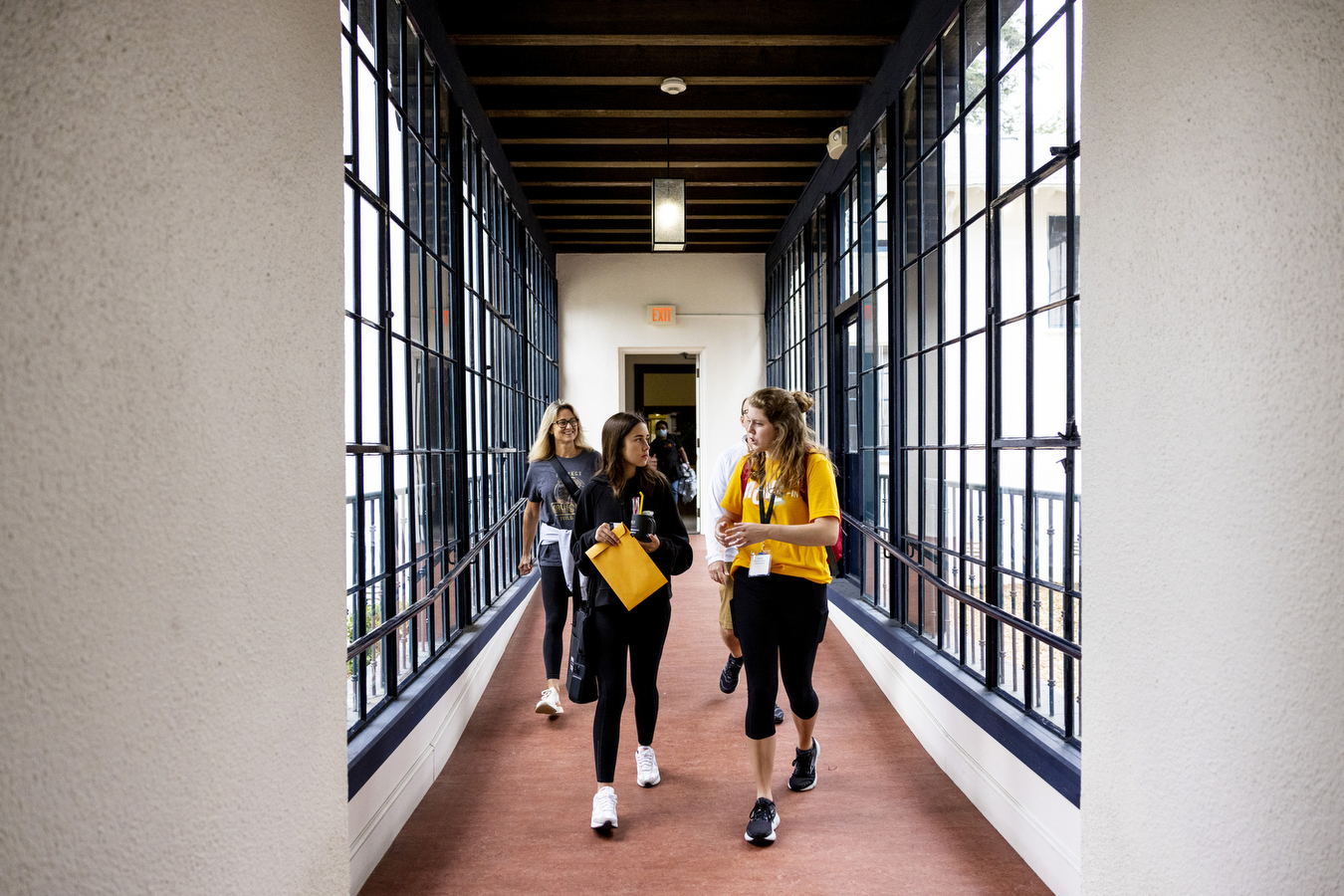 Three students walk down a brightly lit hallway