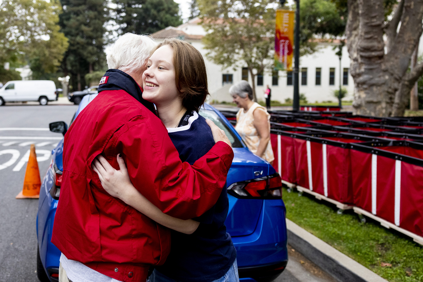 A student hugs their father on the sidewalk at the Northeastern in Oakland campus