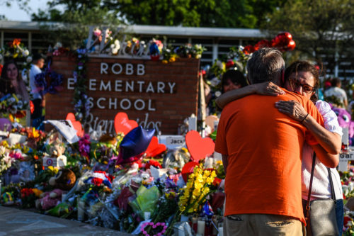 Two people embrace in grief outside a makeshift memorial created after the mass killing at Robb Elementary School