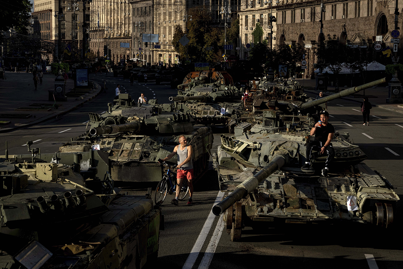 People walk among destroyed military vehicles on a city street