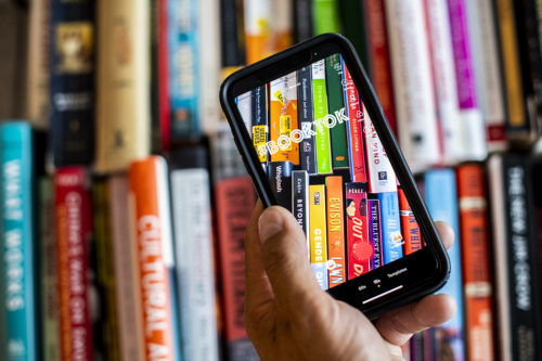 hand holding smartphone taking photo of books on a shelf