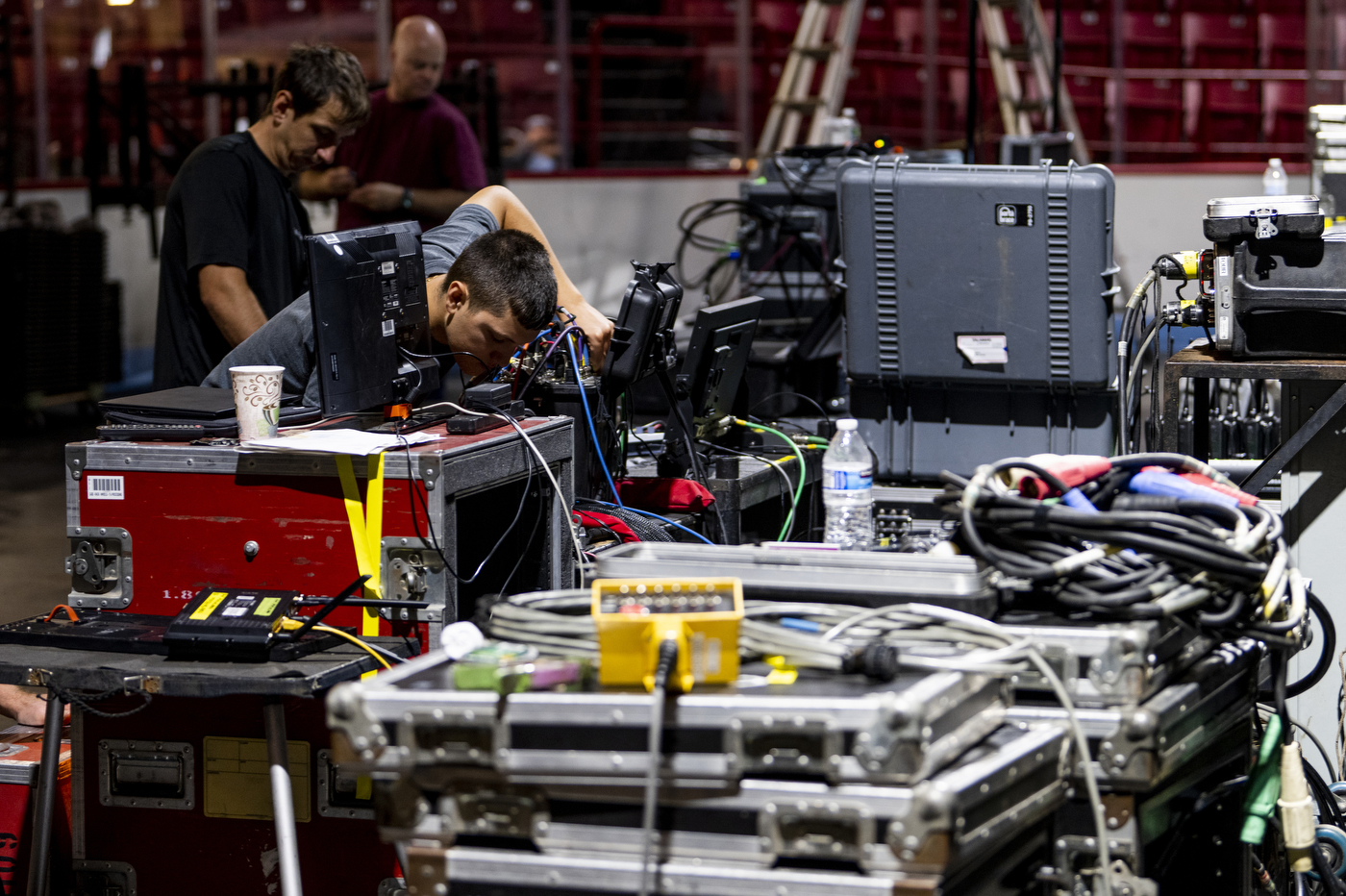 People are working on rows of wires connected to large metal boxes to prepare for Northeastern's Convocation. 