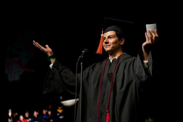 A person wearing a graduation cap and gown is talking into a microphone at Northeastern's 2022 Convocation.