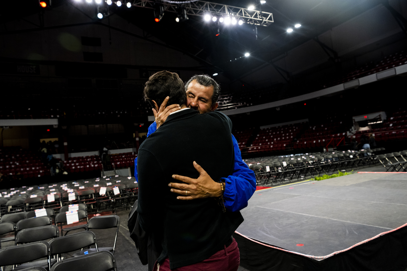 A family at Northeastern's Convocation is hugging in a large arena. 