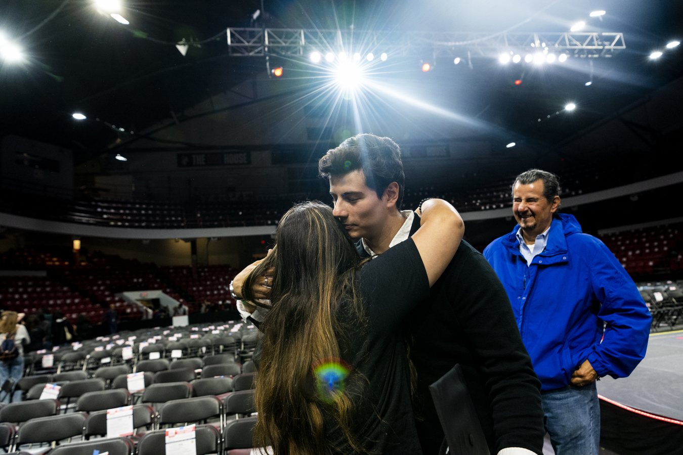 A family at Northeastern's Convocation is hugging in a large arena. 
