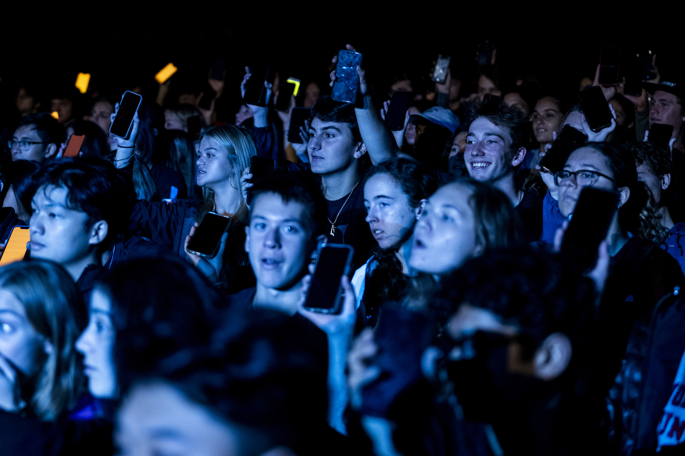 A large crowd is shown in a dimly lit blue light at Northeastern's 2022 Convocation.