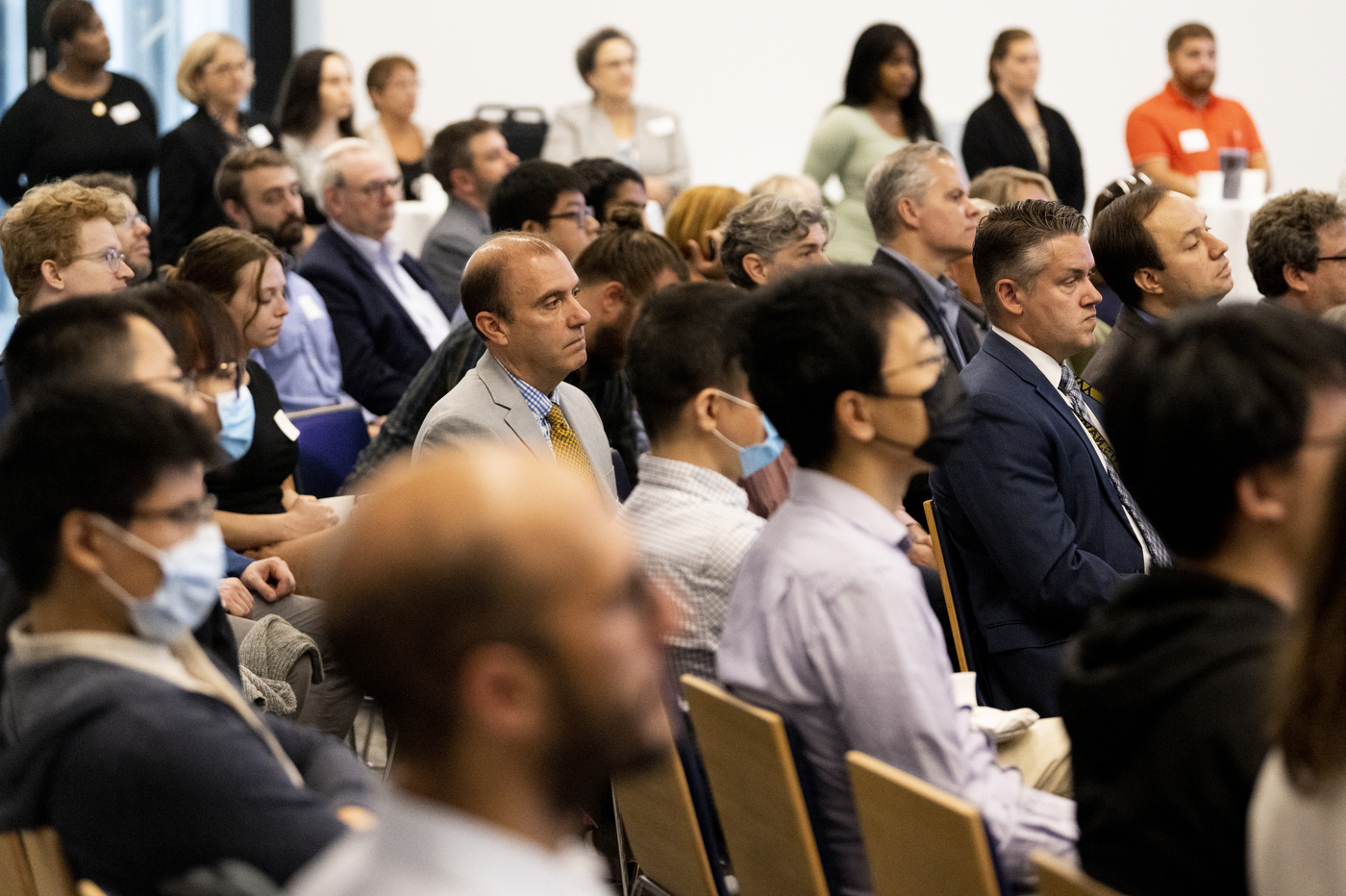A crowd of experts part of the field of quantum technology sit together in a large room.