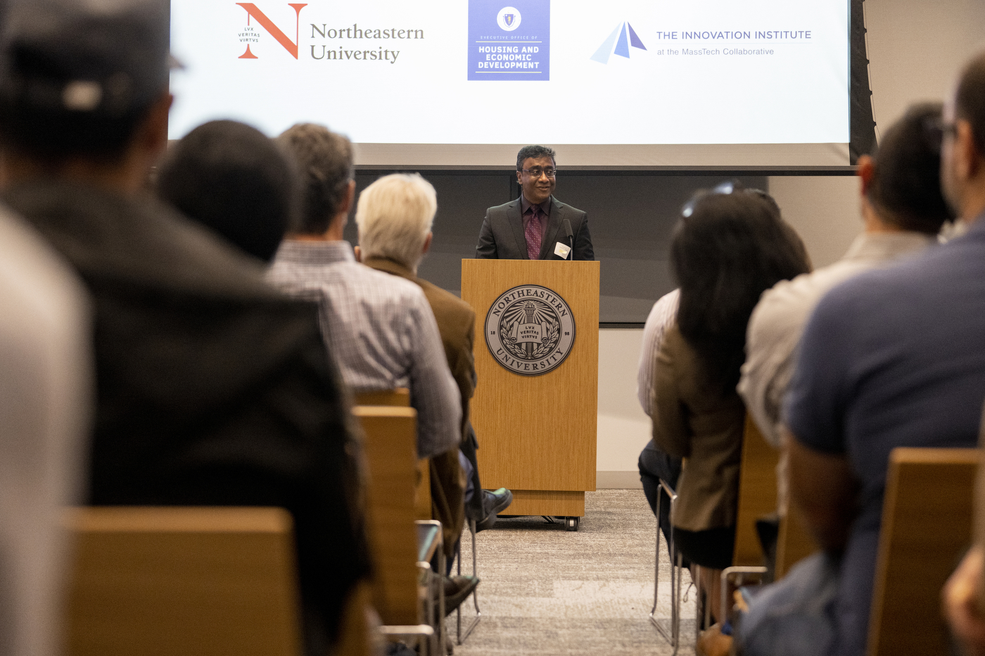 Professor Swastik Kar stands at a podium talking to large crowd about quantum technology. 
