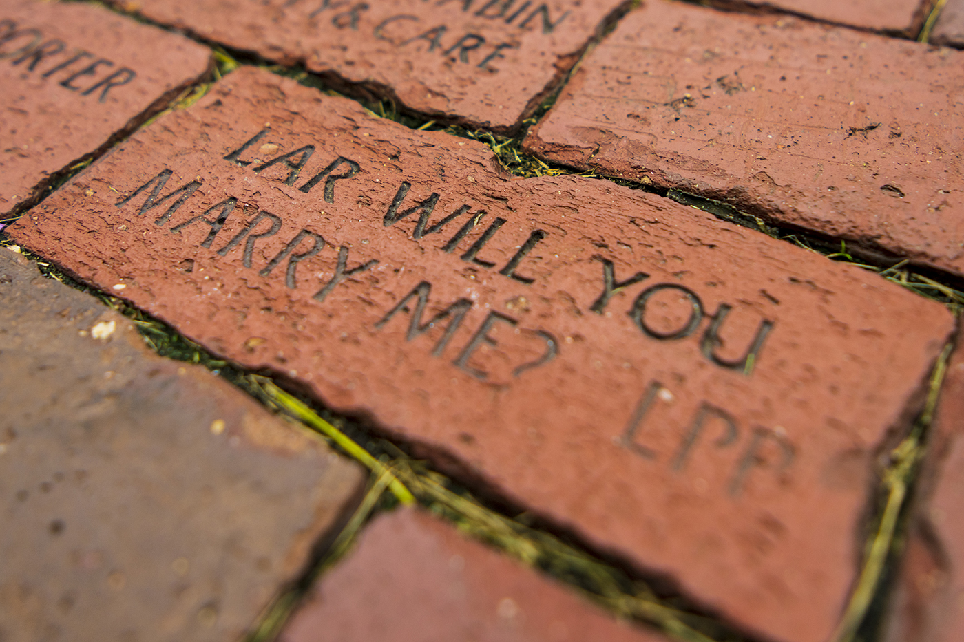 A red brick has black text carved on the top: "Lar, will you marry me? L.P.F." on Northeastern's Boston campus.