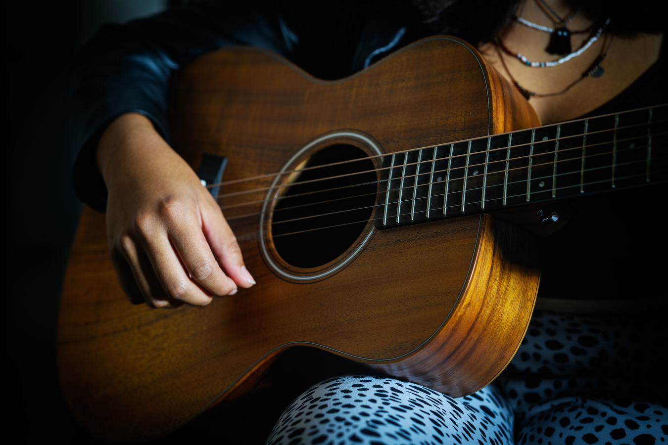 A person is holding an acoustic guitar while playing the instrument. 