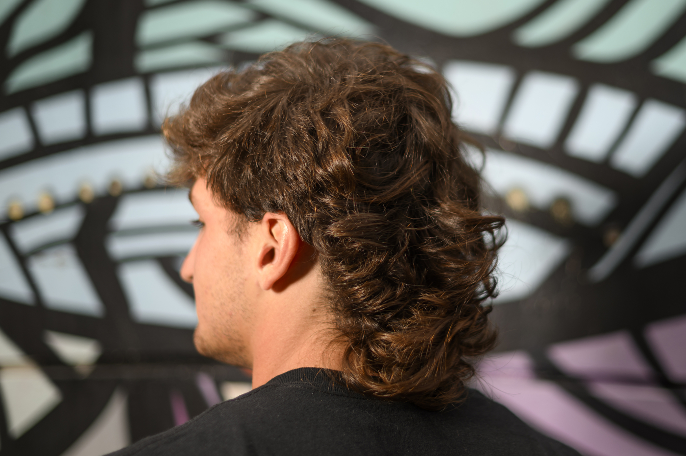 A person has their head slightly turned to the left, displaying the side of their mullet. 