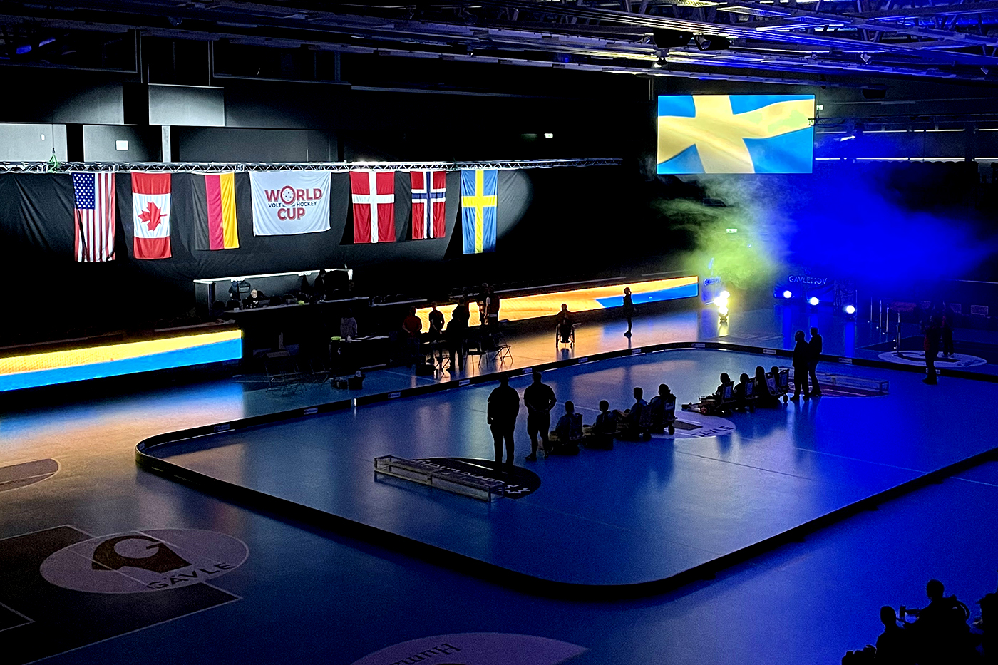 World flags are illuminated over a dark court at the Volt hockey world cup