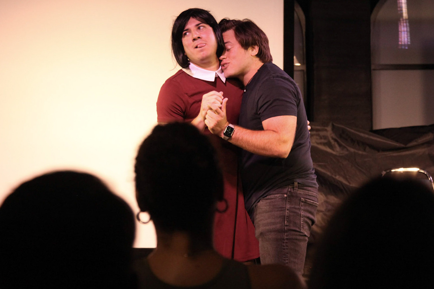 Two actors are dancing together on stage during sketch comedy show. 